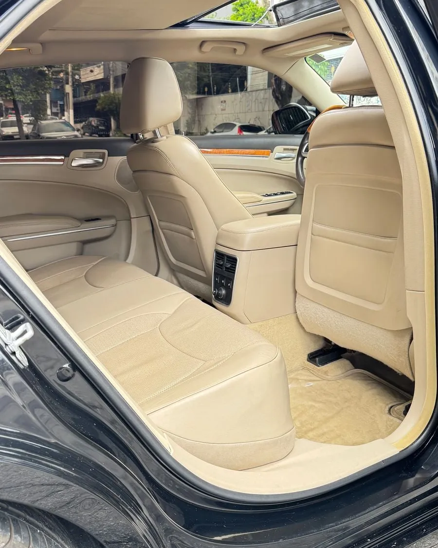 Interior do Chrysler 300C preto visto pela porta traseira direita aberta, banco em couro claro e teto solar