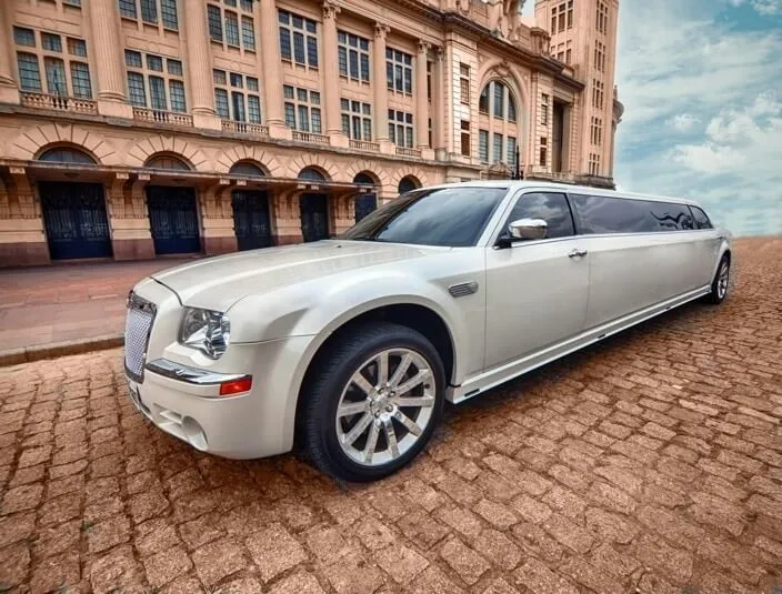 Limousine Chrysler 300C branca em três quartos, estacionada em frente a um edifício histórico