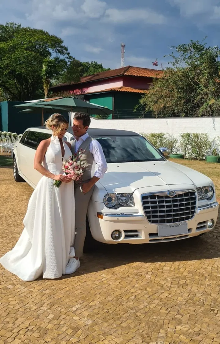 Noivos abraçados em frente à limousine Chrysler 300C branca, momentos antes da cerimônia