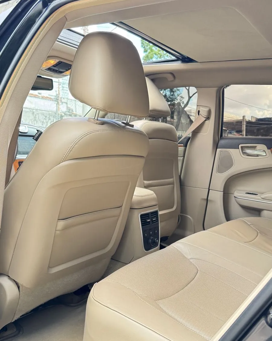 Interior do Chrysler 300C preto visto pela porta traseira esquerda aberta, banco em couro claro e teto solar